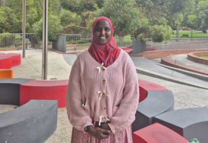 Wearing a headscarf, Ikran stands in the middle of school grounds smiling