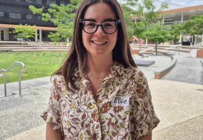 Ellie Robinson wears glasses and smiles at the camera