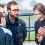 Image of teacher showing students something on phone.